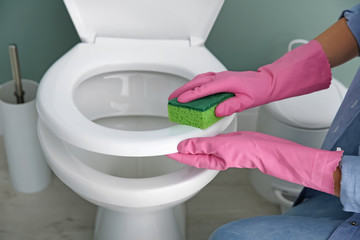 Woman cleaning toilet bowl in bathroom