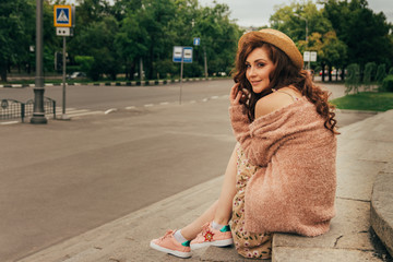 portrait a beautiful girl in a hat, sits on scraps. keeps the hair from the wind. walk around the...
