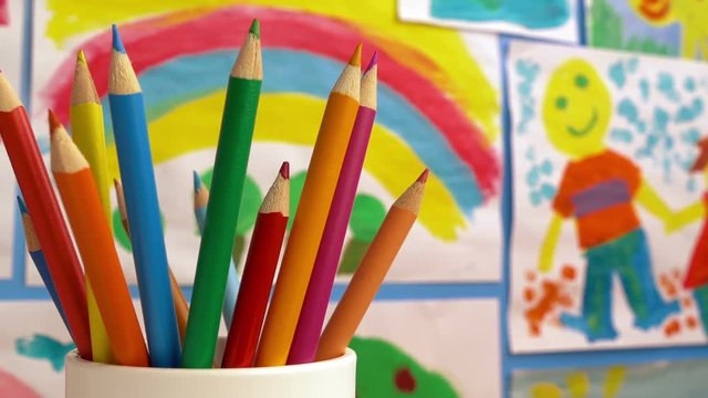 Color Pencils In Classroom With Paintings On Wall