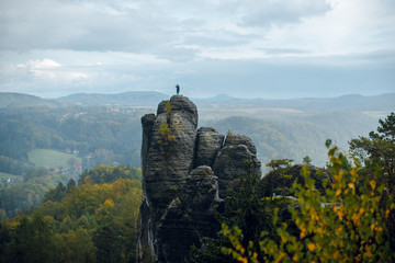Gloomy Autumn landscape of rocky mountains, rocks and forest with colorful trees in Saxon Switzerland National Park on cloudy day. Germany