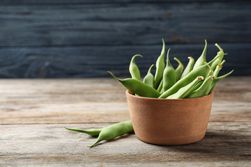 Bowl with fresh green beans on wooden table