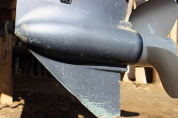 Lower unit – scratched gear case with white aluminium propeller outboard motor on the transom of the boat