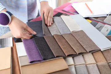 Young woman choosing among upholstery fabric samples, closeup. Interior design