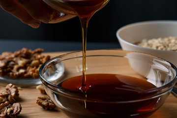 Healthy Breakfast ingredients: honey, walnuts, oatmeal on a dark background. Healthy diet. Close up. Honey pouring