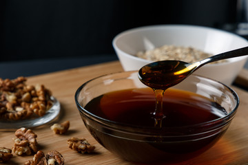 Healthy Breakfast ingredients: honey, walnuts, oatmeal on a dark background. Healthy diet. Close up. honey dripping from spoon
