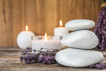 Spa stones with lavender flowers and candles on table