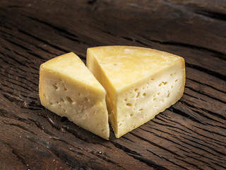 Pieces of homemade cheese on the wooden background.