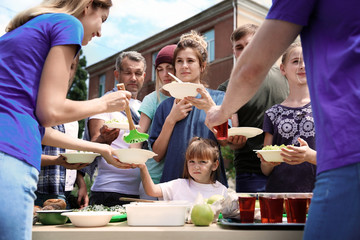 Volunteers serving food for poor people outdoors