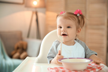 Fototapeta premium Cute little girl eating healthy food at home