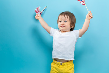 Happy toddler boy waving American flags on a blue background