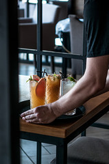 waiter served drinks on the table. Fresh alcohol cocktail lemonade in man hand.