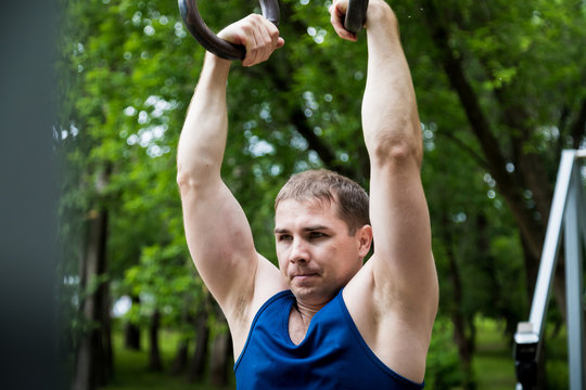 Attractive fitness man doing exercises in park