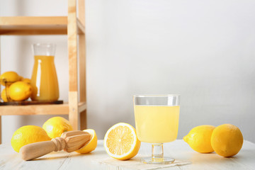 Glass with fresh lemon juice and fruits on table