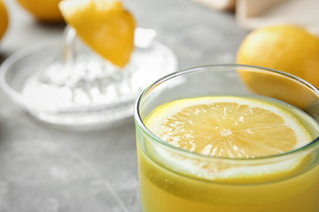 Glass with fresh lemon juice on table, closeup