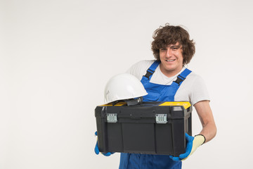 Happy handsome builder with helmet and toolbox laughing at camera.