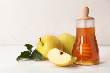 Jar of honey, apples and dipper on wooden table