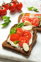 Fototapeta na wymiar Toast bread with cherry tomatoes and mozzarella cheese on marble board, closeup