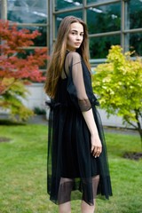 gorgeous young woman in elegant black dress posing outdoors