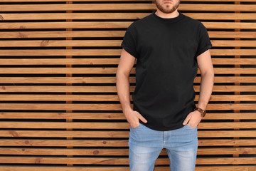 Young man wearing black t-shirt against wooden wall on street. Urban style