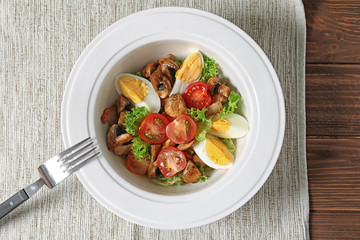 Plate with delicious fresh salad on table, top view