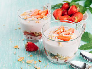 Bowl with fresh strawberry yogurt. Diet yoghurt and granola with slice of berries in a glass on a wooden table. Copy space