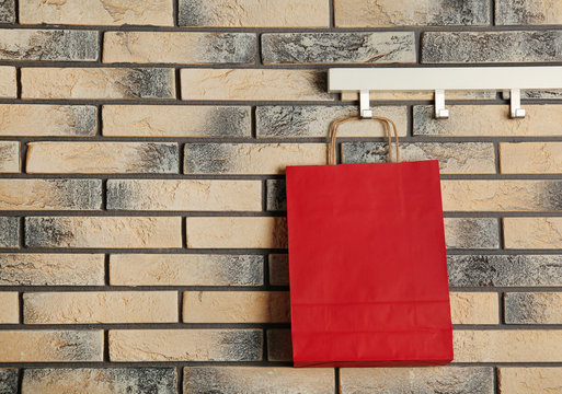 Rack with paper shopping bag on brick wall