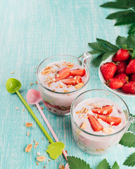 Bowl with fresh strawberry yogurt. Diet yoghurt and granola with slice of berries in a glass on a wooden table. Copy space