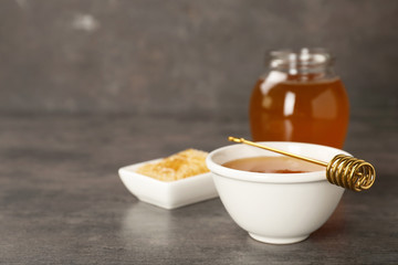 Bowl of tasty fresh honey and dipper on table