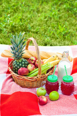 picnic basket, fruit, juice in small bottles, apples, pineapple summer, rest, plaid, grass Copy space