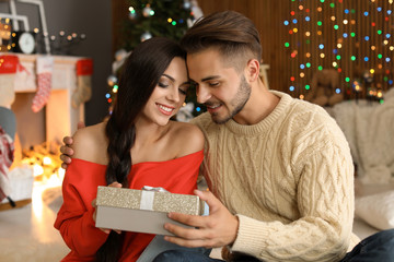 Young couple with Christmas gift box at home