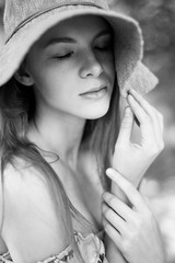 A sophisticated red-haired girl in a simple linen dress, in a light wide-brimmed hat. Model look. Natural beauty. Artistic portrait