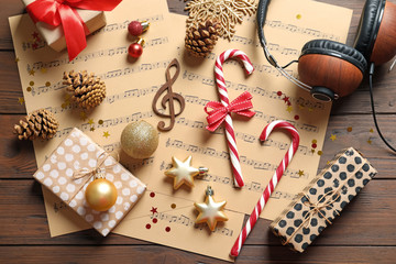 Flat lay composition with Christmas decorations, music sheets and headphones on wooden background