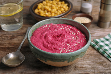 Bowl with tasty creamy beet hummus on wooden table
