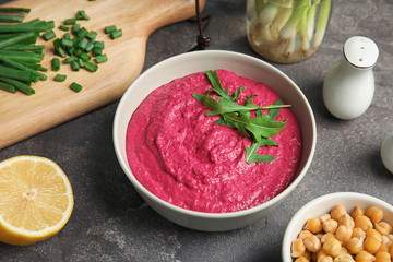 Bowl with tasty creamy beet hummus on dark table