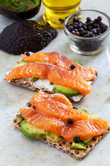 Two Crisp sandwiches with avocado and salmon. Marble background. Selective focus.