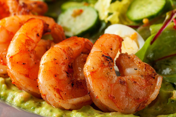 Delicious grilled shrimps served with salad with green vegetables - lettuce, cucumber