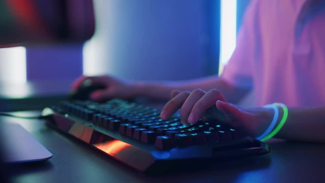 Close-up on the Hands of the Gamer Playing in the Video Game on a Keyboard and Using Mouse. Stylish Arcade Neon Bright Red, Pink, Violet, Green Colors.