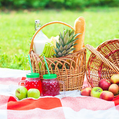 picnic basket, fruit, juice in small bottles, apples, pineapple summer, rest, plaid, grass Closeup
