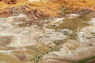 Aerial view on multicolored red, orange and yellow striped hills under the bright blue sky in Kiin-Kerysh (Valley of Spirits) Eastern Kazakhstan