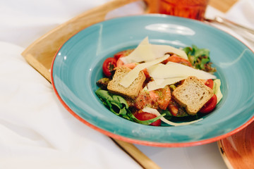 Breakfast or lunch in bed of a panzanella salad with croutons and a bagel with fresh lettuce, two drinks and French fries on a tray in colorful plates