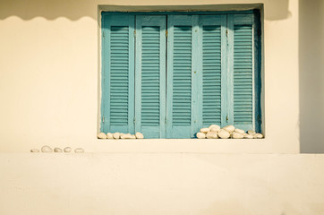 Stones stacked up at the window with wooden shutters on the beach shore Leptokarya 