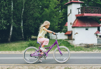 side view of cute little child riding bicycle on road