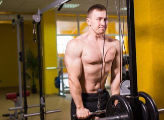 Naklejka premium Muscular man working out in gym doing exercises, strong male naked torso abs