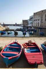 Traditional red and blue fishing boats in Monopoli port near Castle of Carlo V, Apulia, Bari...