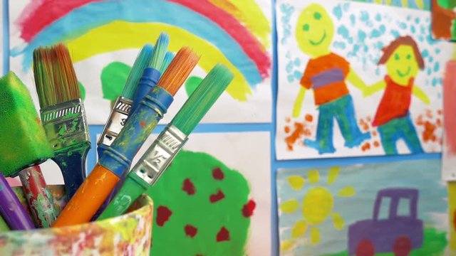 Paint Brushes In Classroom With Paintings On Wall