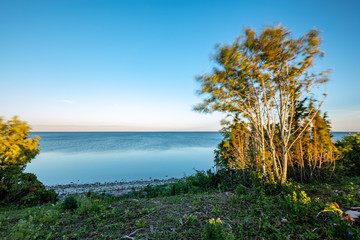 dramatic sunrise over the baltic sea with rocky beach and trees on the shore
