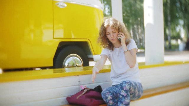 young woman outdoors by yellow vagon car listening music in headphones using smartphone - relaxing, enjoying, concept of technology and travel