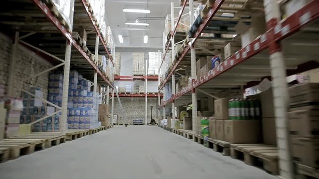 The movement of the camera between shelves with household chemicals in a large warehouse