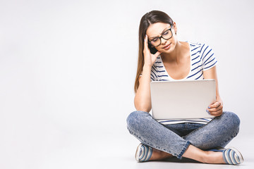 Business concept. Portrait of depressed woman in casual sitting on floor in lotus pose and holding laptop isolated over white background. Using phone.