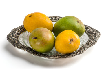mangoes on glass plate isolated on white background
